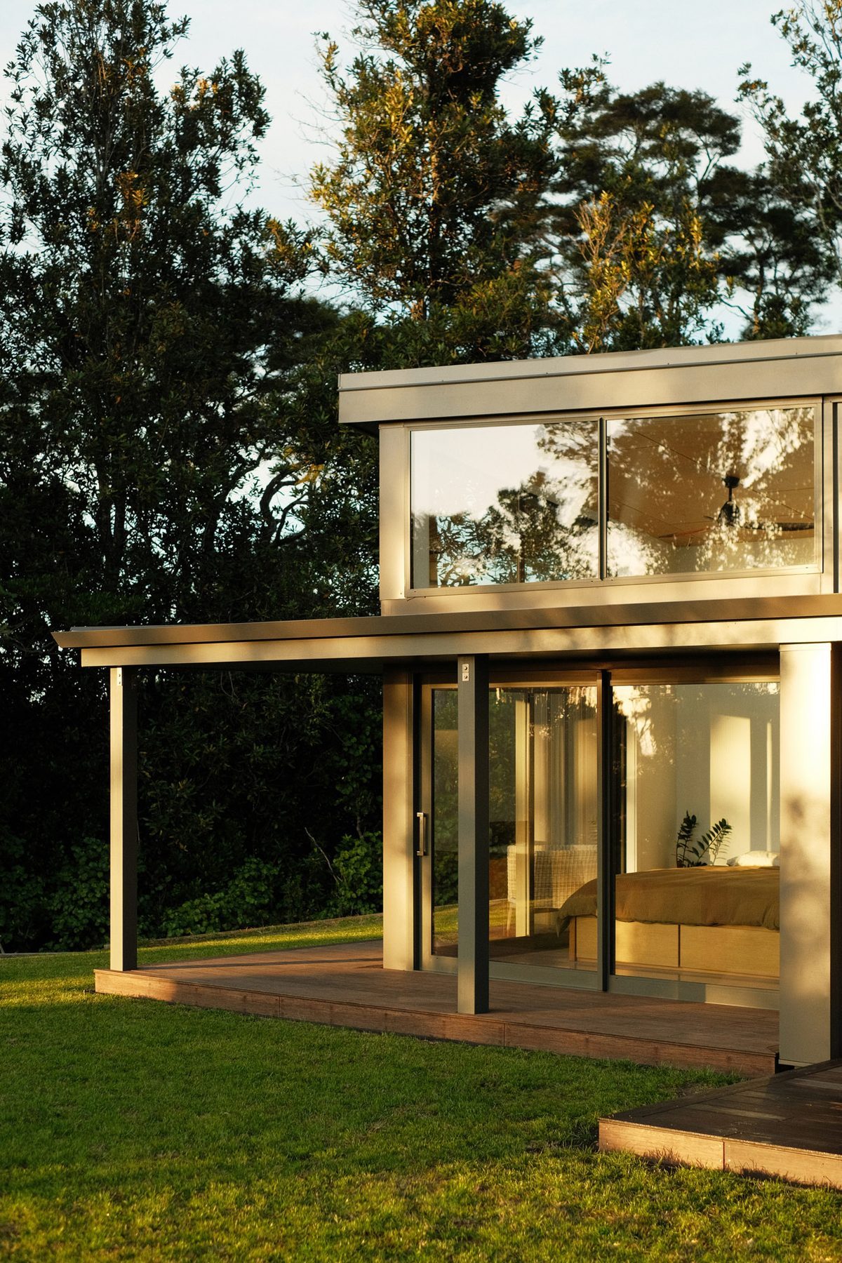 Dusk: the fully glazed corner, lit from within.